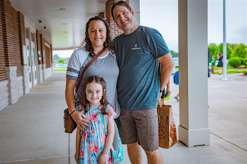 A family of three smiles